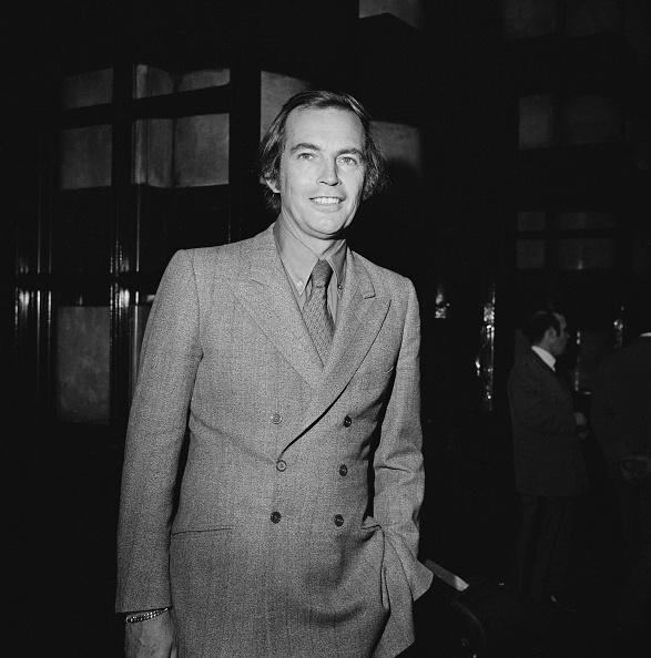 Das schwarz-weiß Foto zeigt den südafrikanischen Chirurgen Christiaan Barnard. Er trägt Hemd, Krawatte und ein zugeknöpftes Sakko mit doppelter Knopfreihe. Seine linke Hand hat er in der Hosentasche, während er lächelnd in die Kamera schaut.