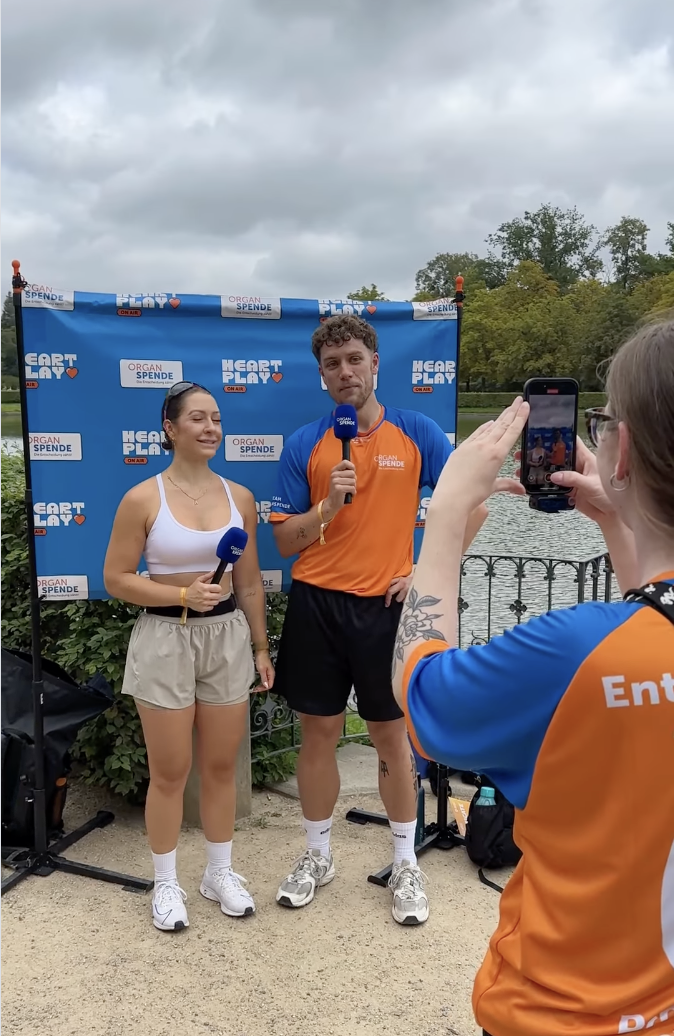 Das Bild zeigt eine L&auml;uferin und Smitty bei einem Interview und eine Person, die die beiden filmt.