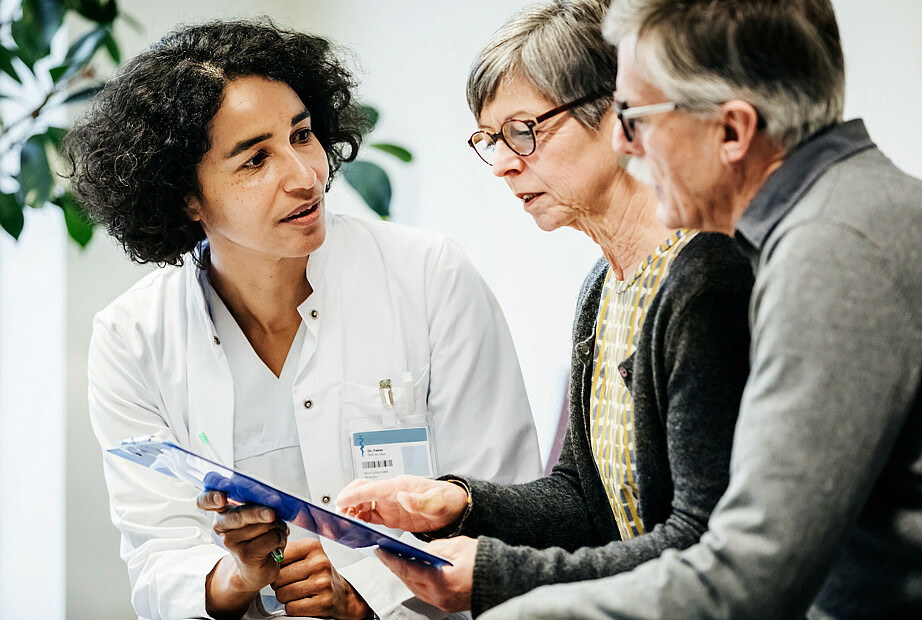 Zwei ältere Menschen, eine Frau und ein Mann, lassen sich von einer Ärztin beraten.