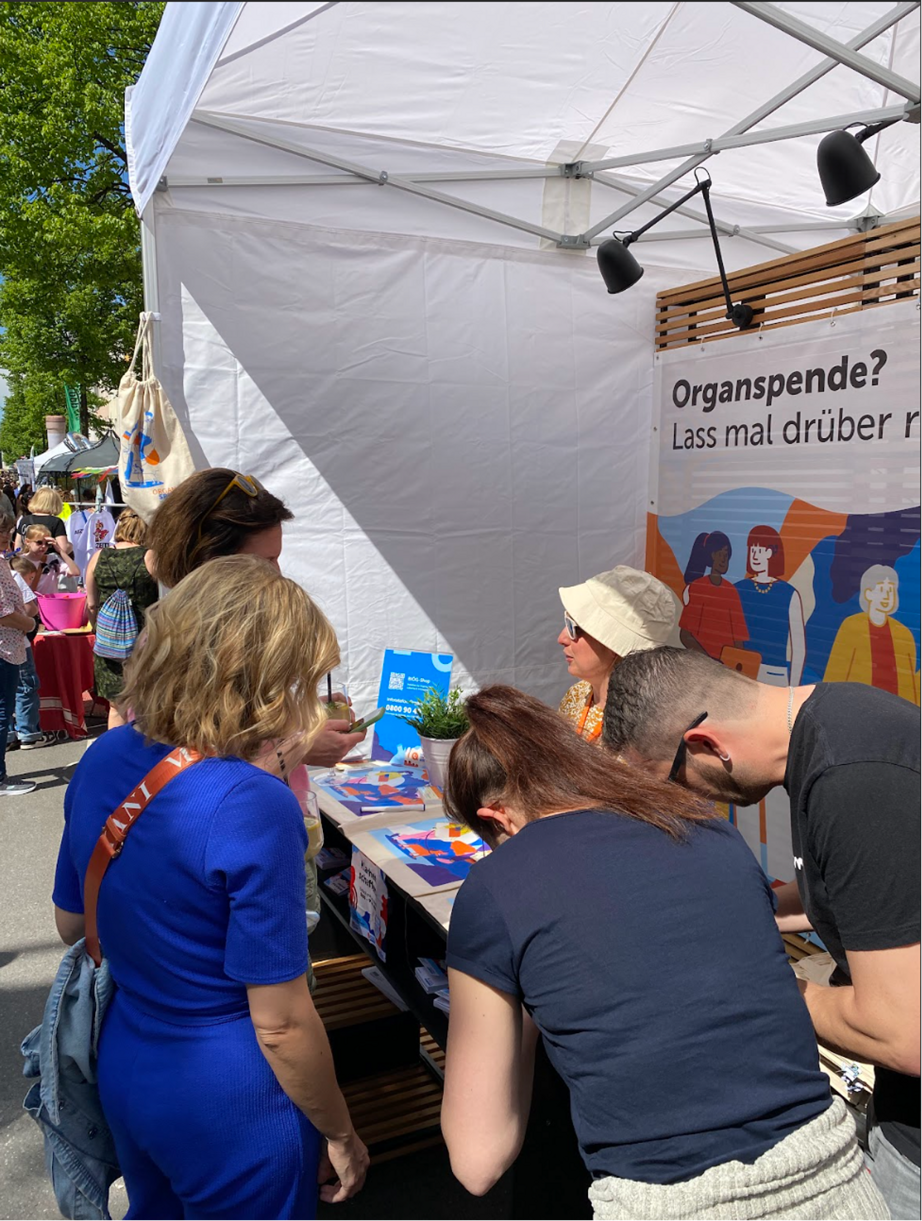 Das Bild zeigt einen belaufenen Stand des BI&Ouml;G Organspende und Menschen, die Organspendeausweise unterschreiben.