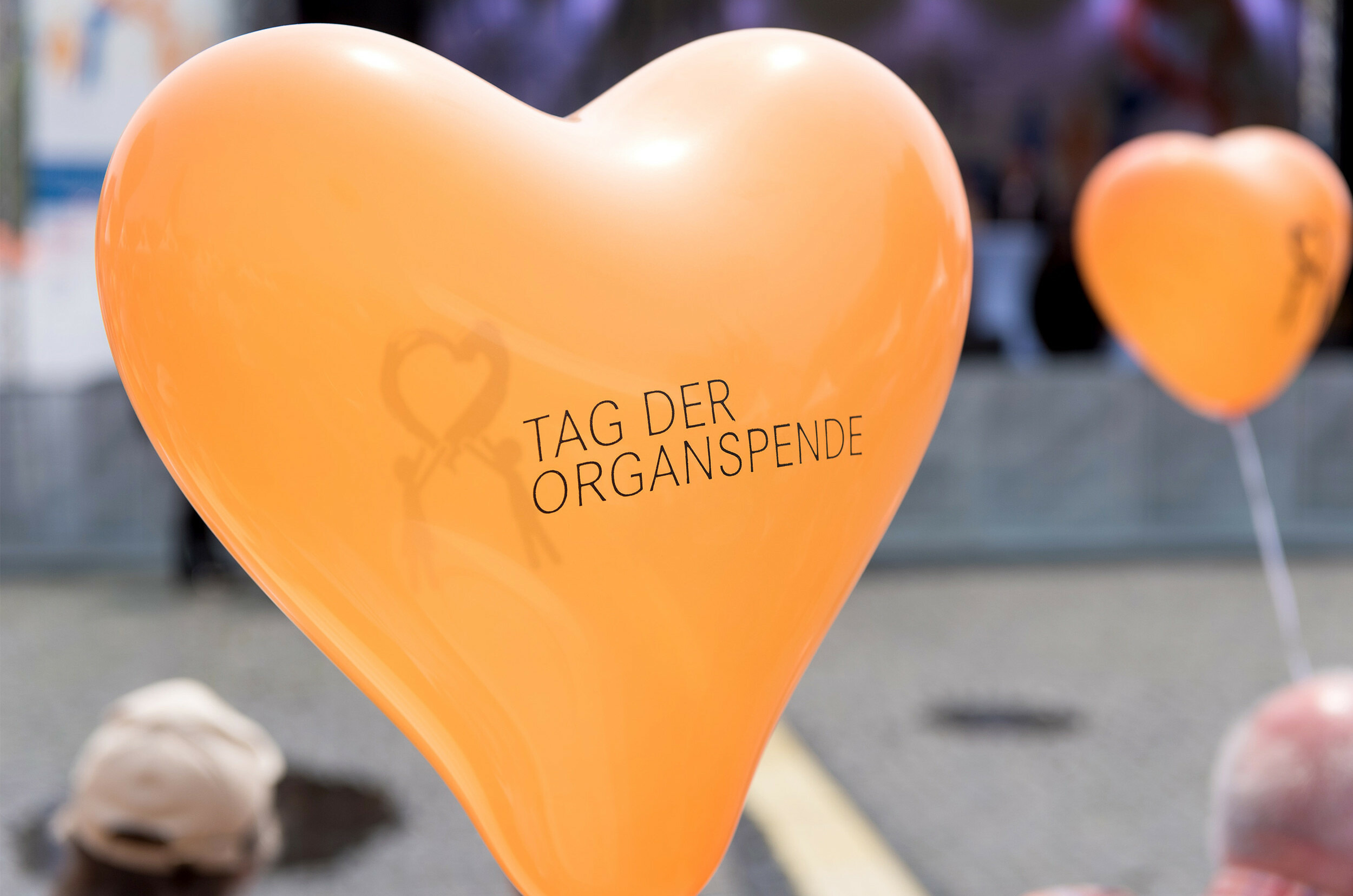 Zu sehen ist ein orangefarbener Herzballon auf dem „Tag der Organspende" steht.