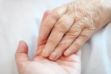 Die Hand eines &auml;lteren Menschen liegt in der Hand eines j&uuml;ngeren Menschen.