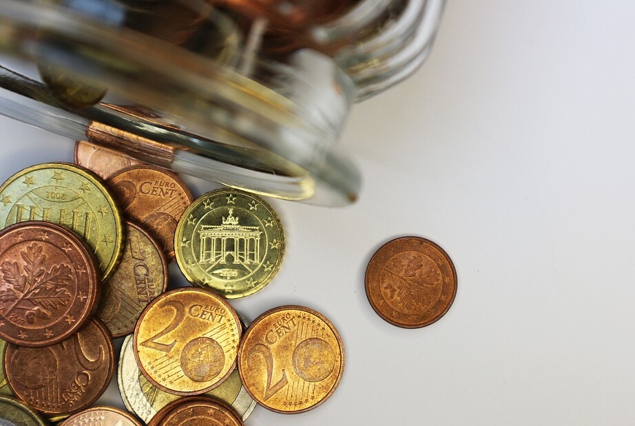 Aus einem umgekippten Glas sind unterschiedliche Euro-Münzen gefallen.