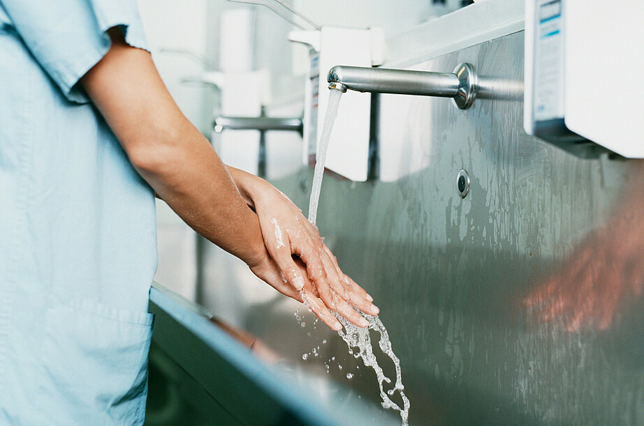 Ein Chrirurg wäscht sich an einem Krankenhauswaschbecken die Hände.
