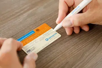 Eine Person f&uuml;llt einen Organspendeausweis aus. Man sieht nur die H&auml;nde, die einen Stift und den Ausweis auf dem Tisch halten.