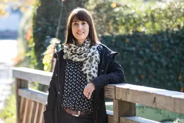 Manja Elle steht an einem sonnigen Tag auf einer Br&uuml;cke und l&auml;chelt in die Kamera. 