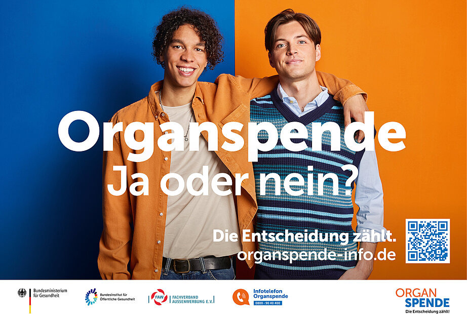 Kampagnenmotiv im Querformat, auf dem sich zwei junge Männer freundschaftlich die Arme übereinanderlegen.