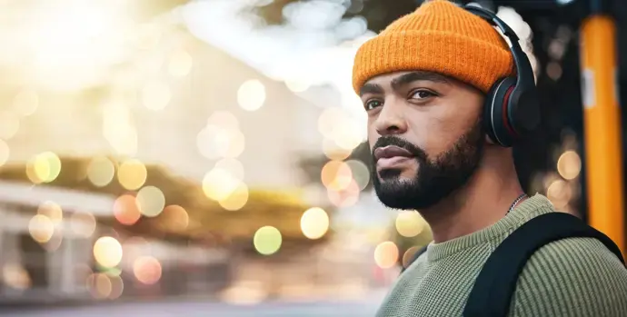 Organspende-Podcasts Mann, der mit einer orangefarbenen Mütze und Kopfhörern in Ferne blickt